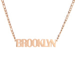 A rose gold-colored necklace with the name 'BROOKLYN' written in bold, all-capital letters.