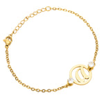 A gold-toned bracelet with two round charms and a personalized initial in the center, complemented by clear fancy stones.