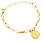 A gold-colored bracelet with a sunburst design, featuring a central letter 'B' on a chain structure, indicating a personalized touch.
