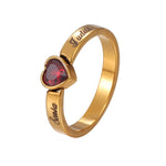 Gold ring with a red heart-shaped gemstone on a white background
