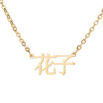 A gold-plated stainless steel necklace with Japanese characters engraved on it, on a white background.